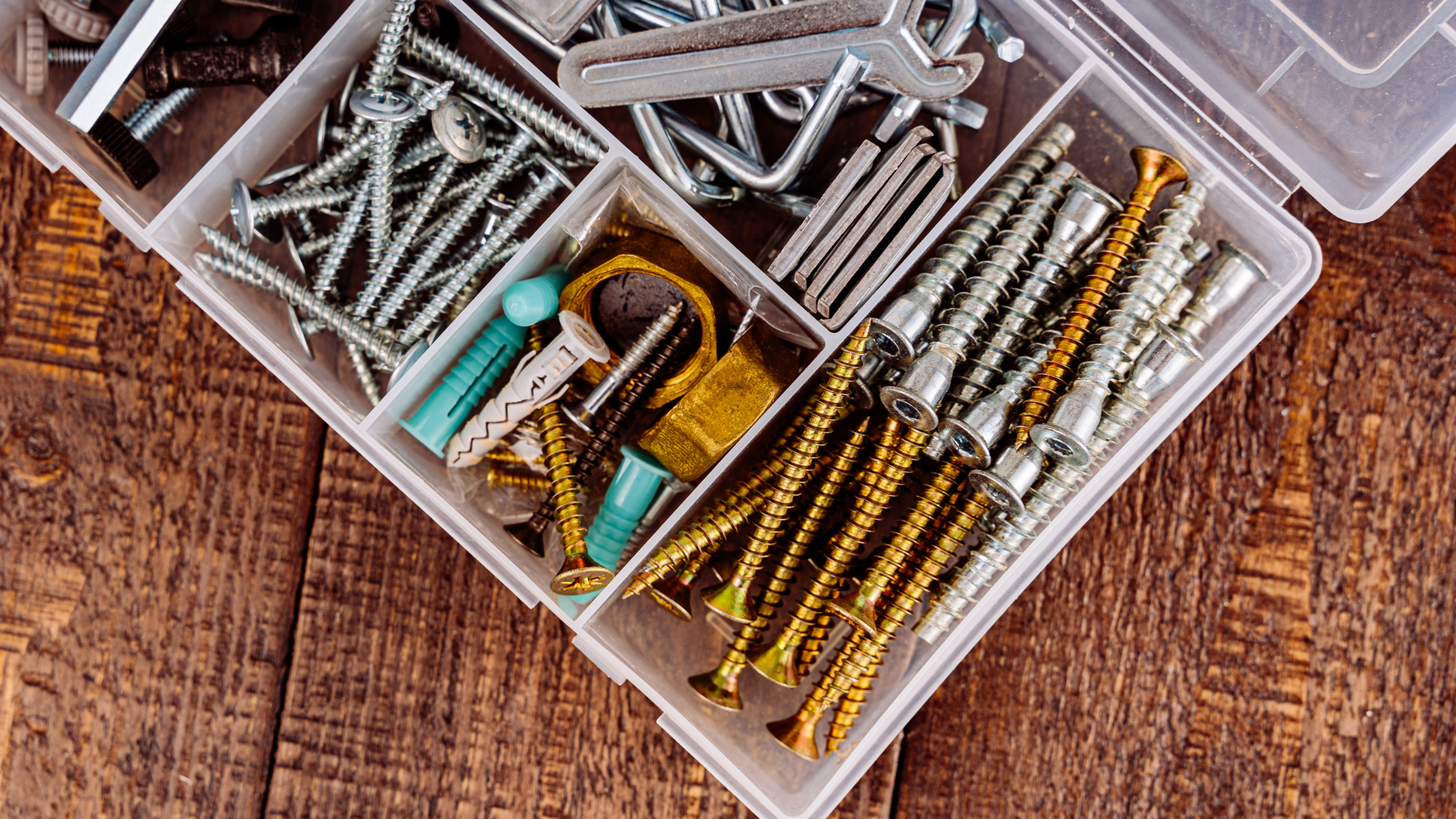 plastic box of metal screws on wooden table